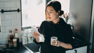 Woman looking at energy bill while having a cup of tea