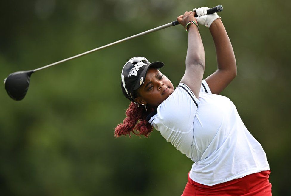 Chanelle Wangari Mwangi takes a swing with a golf club,