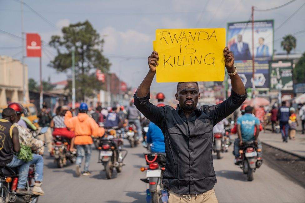 A man holds a sign saying "Rwanda is killing" during a march in Goma denouncing what protesters say is the silence of the international community about the ongoing fighting in North Kivu province, on the border with Rwanda. Photo dated 19 February.
