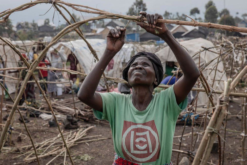 A woman builds a tent frame using pieces of wood in a camp on the outskirts of Goma, in eastern Democratic Republic of Congo.