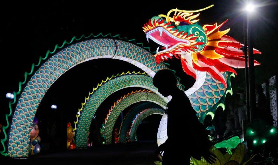 A visitor is silhouetted while passing by the statue of a dragon for the upcoming Chinese New Year celebrations in Banting, Malaysia