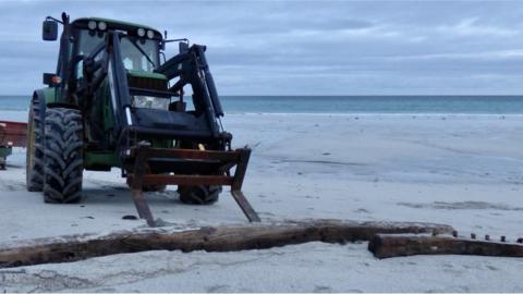 Tractor removing wreckage from beach