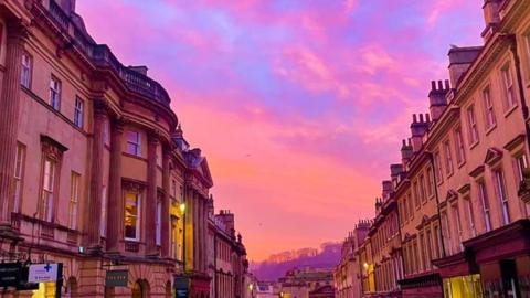 A bright pink and orange sunrise above Milsom Street in Bath