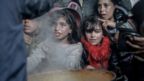 Palestinian children wait in front of a big pot of food distributed by charity organizations in Gaza City, Gaza on February 26, 2024