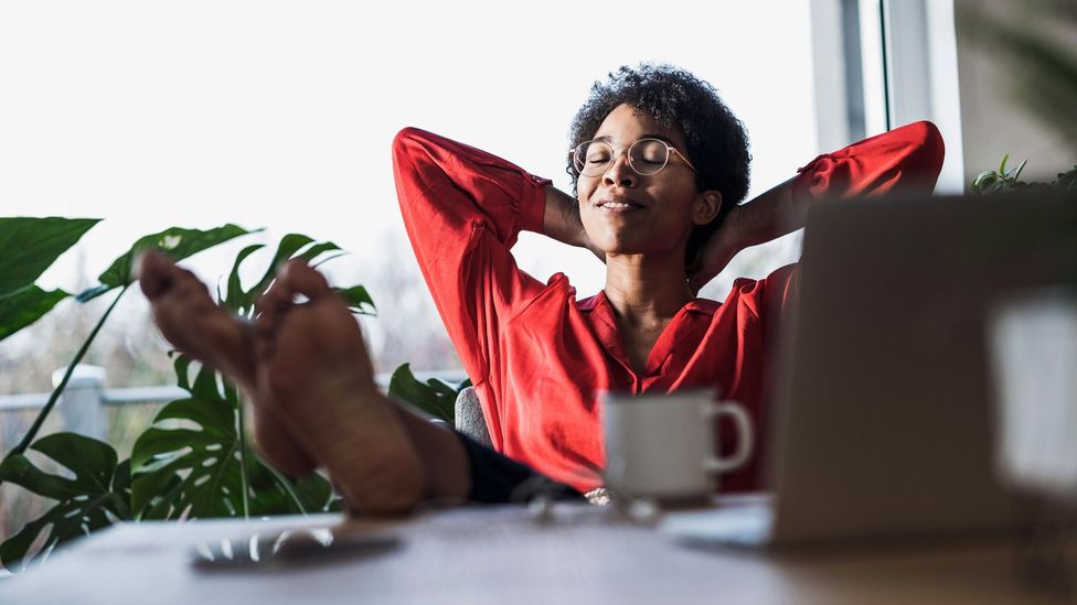 woman reclined in office with feet on desk (Credit: Alamy)